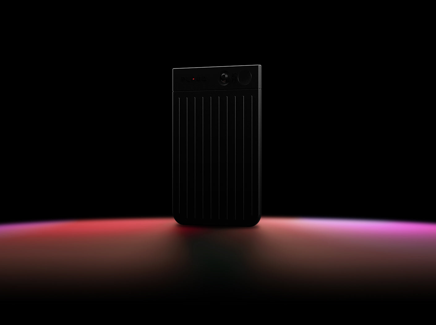 A black Plaud Note stands upright on a dark surface illuminated by a red and purple light gradient.