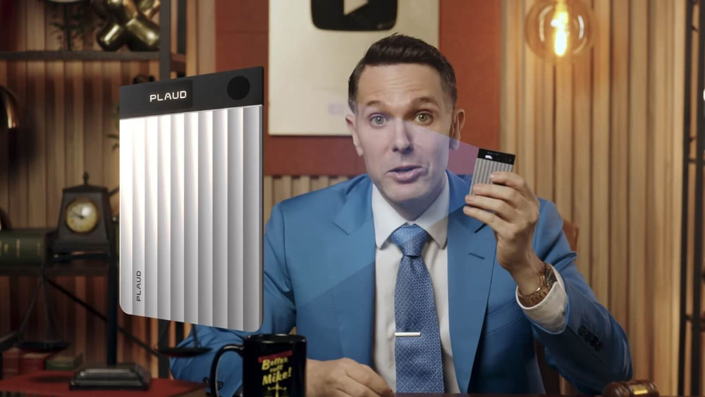 A man in a blue suit presents a silver Plaud Note Pro, holding one in his hand while a larger one floats beside him.